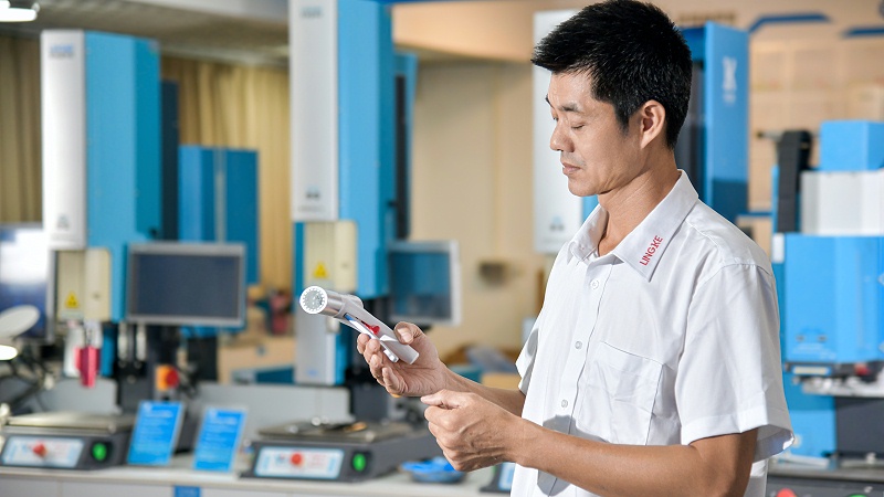 穿白制服男子手持物件在工厂内